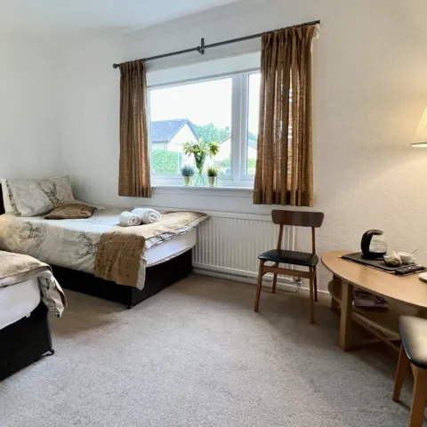 Room 3, two single beds and a chair by the window