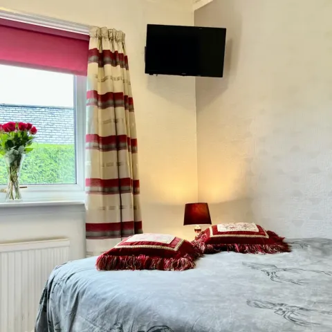 Room 5, a double bed with flowers and a bright window